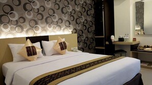 A modern hotel room with a large bed, a desk, and a mirror. - Jolin Hotel (Makassar)