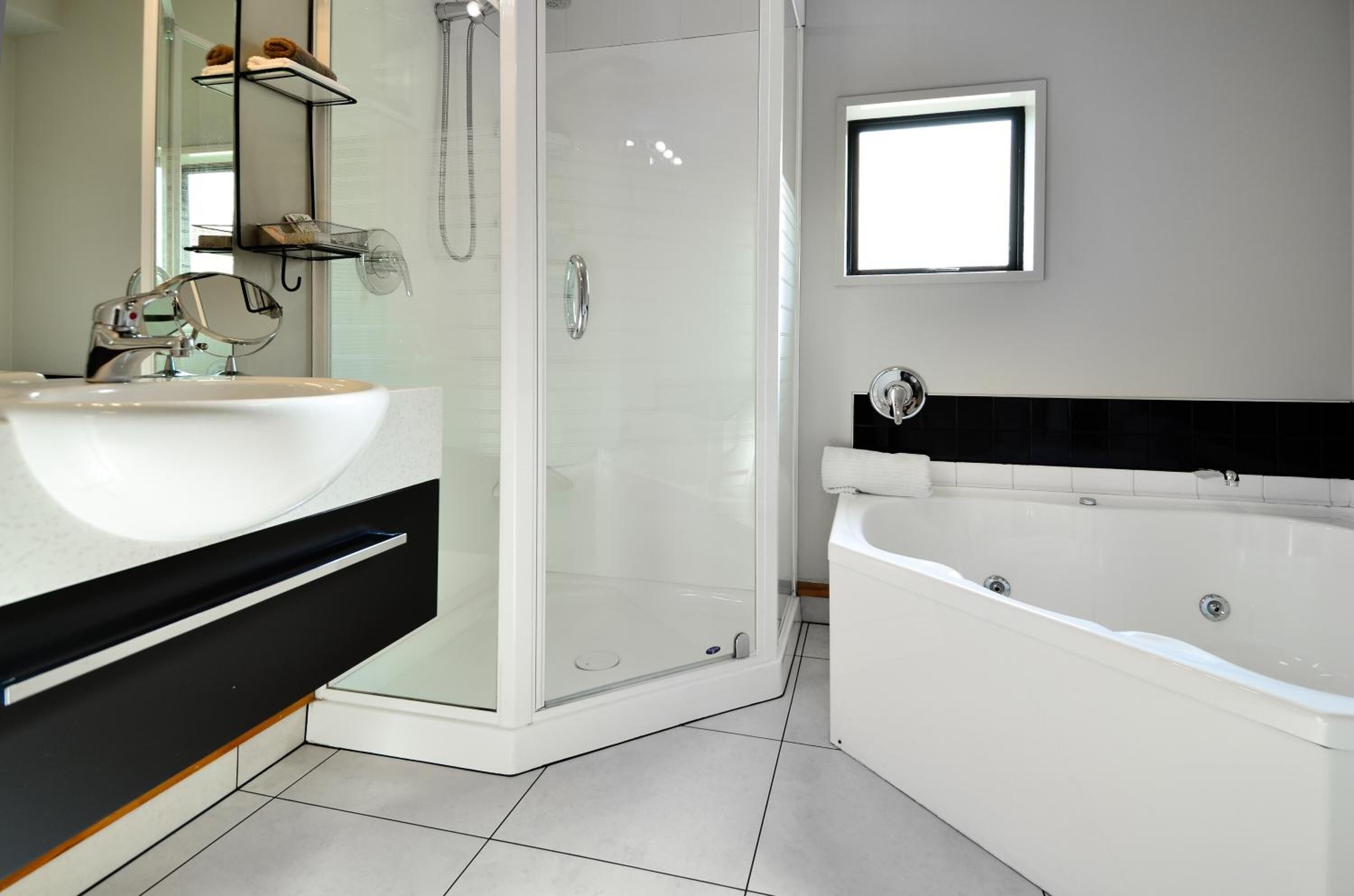 A modern bathroom with a large white bathtub, a glass-enclosed shower, and a dual sink vanity.