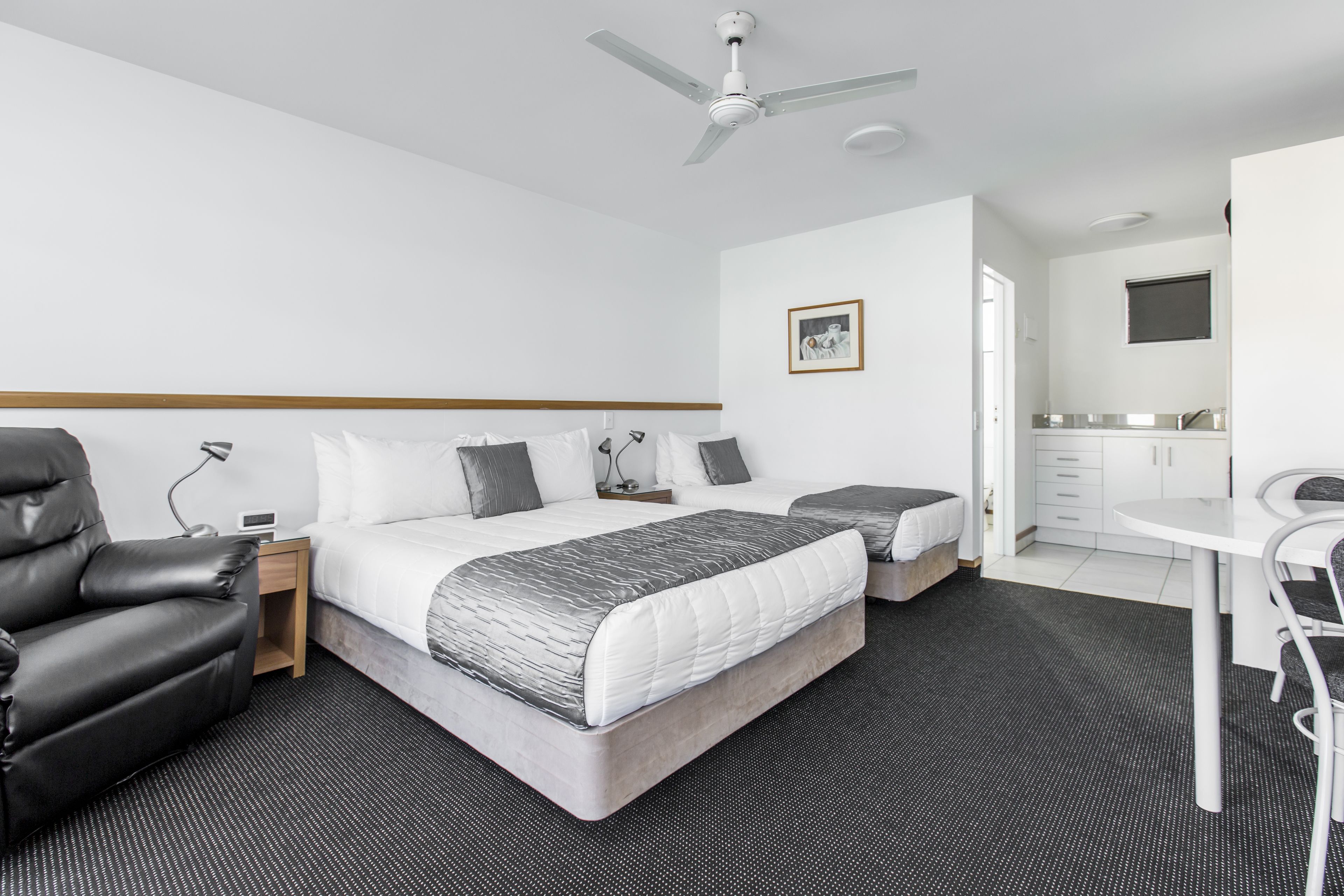 Une chambre d’hôtel moderne équipée d’un grand lit, d’un bureau, d’une chaise et d’un ventilateur de plafond.