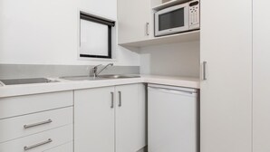 Une cuisine moderne avec des meubles blancs, un four à micro-ondes encastré, un lave-vaisselle et une fenêtre au-dessus de l’évier.