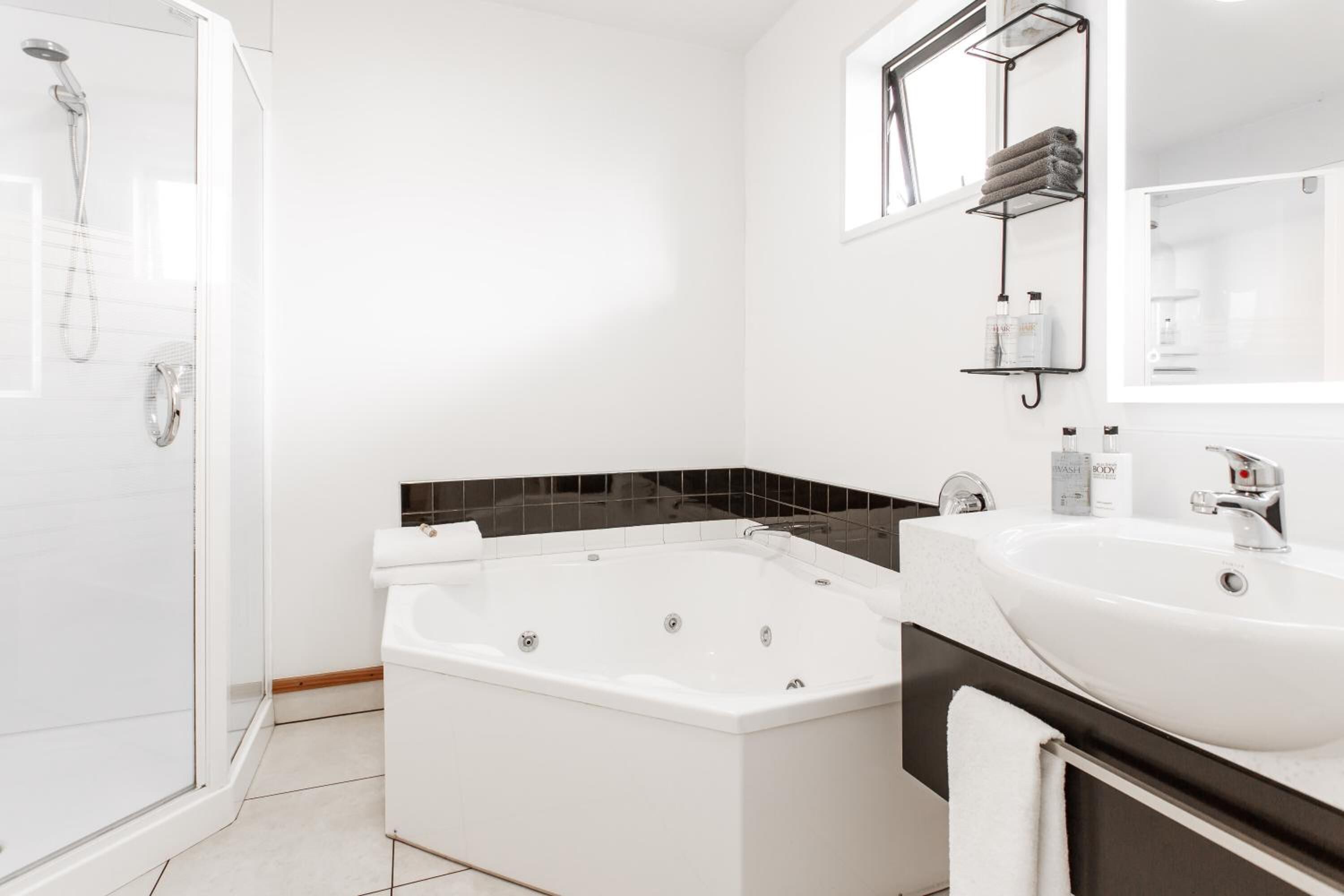 A modern bathroom with a glass-enclosed shower, a freestanding bathtub, and a vanity with a large mirror.