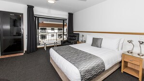 Une chambre d’hôtel avec un lit, une chaise, un bureau, une lampe et un ventilateur de plafond.