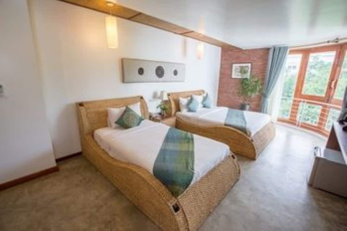 A room with two wicker beds, a brick wall, and a large window.