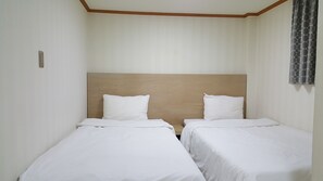 A hotel room with two single beds, wooden headboards, white bedding, and a window with a patterned curtain. - Hotel Daewoo Inn (Seoul)