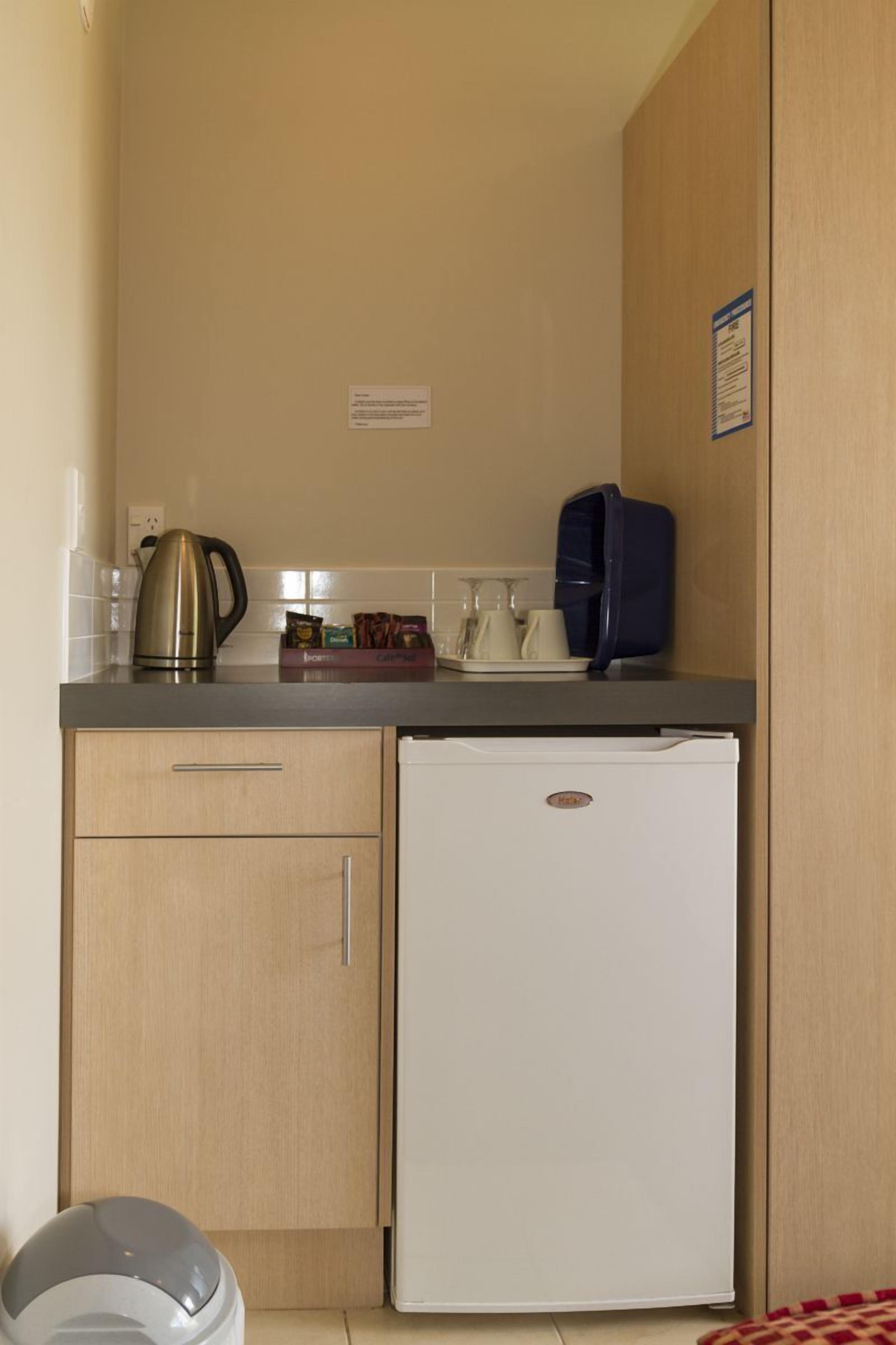A compact kitchenette with a coffee maker, tea pot, and a small refrigerator.