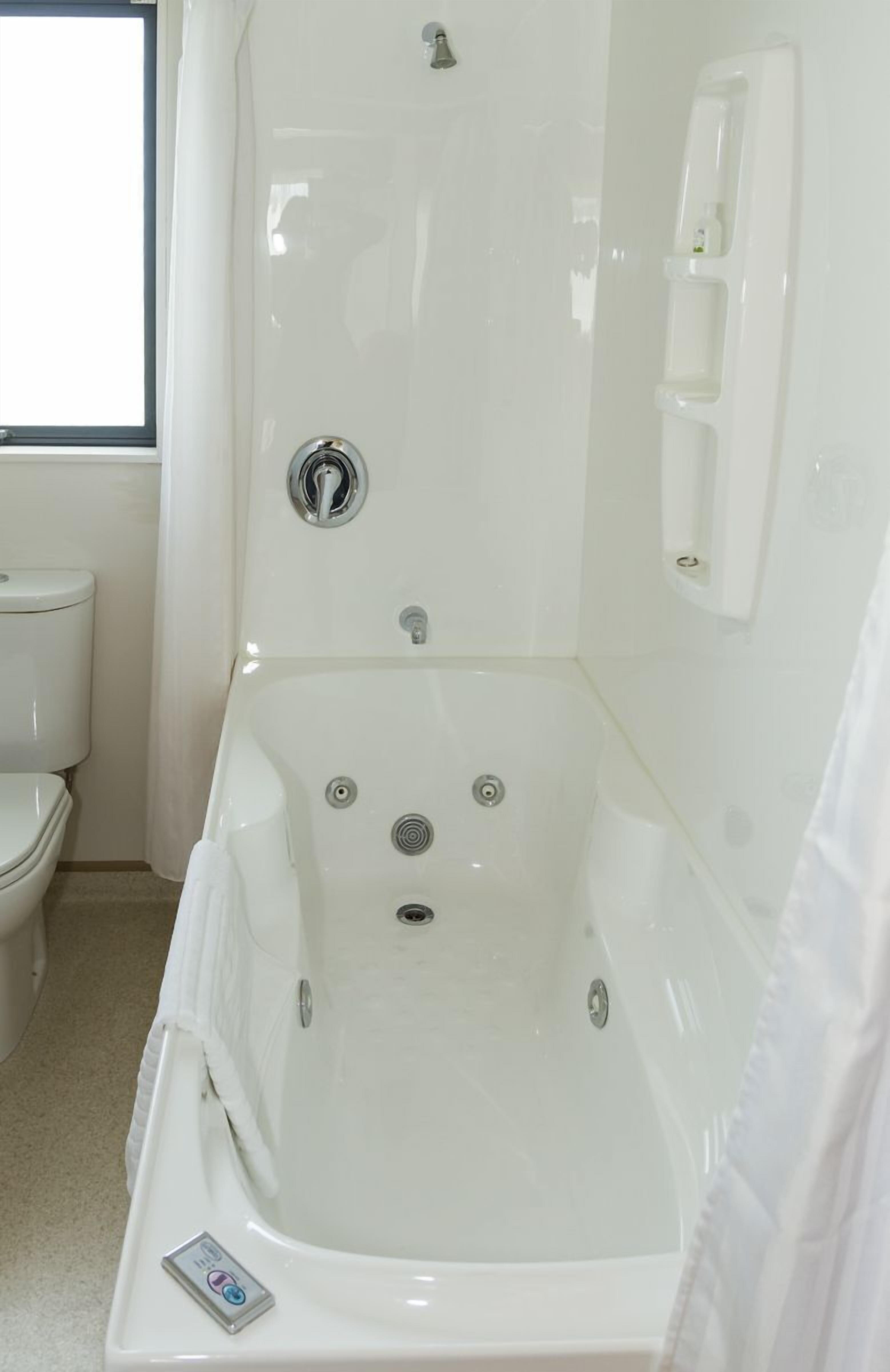 A white bathroom with a bathtub, toilet, and a window.