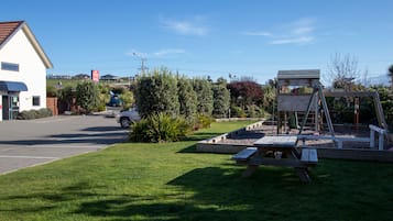A hotel with a reception area, a parking lot, and a playground with a wooden structure.