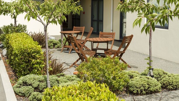 A patio area with outdoor seating and a variety of shrubs and small trees. - Bella Vista Motel Kaikoura (Kaikoura)