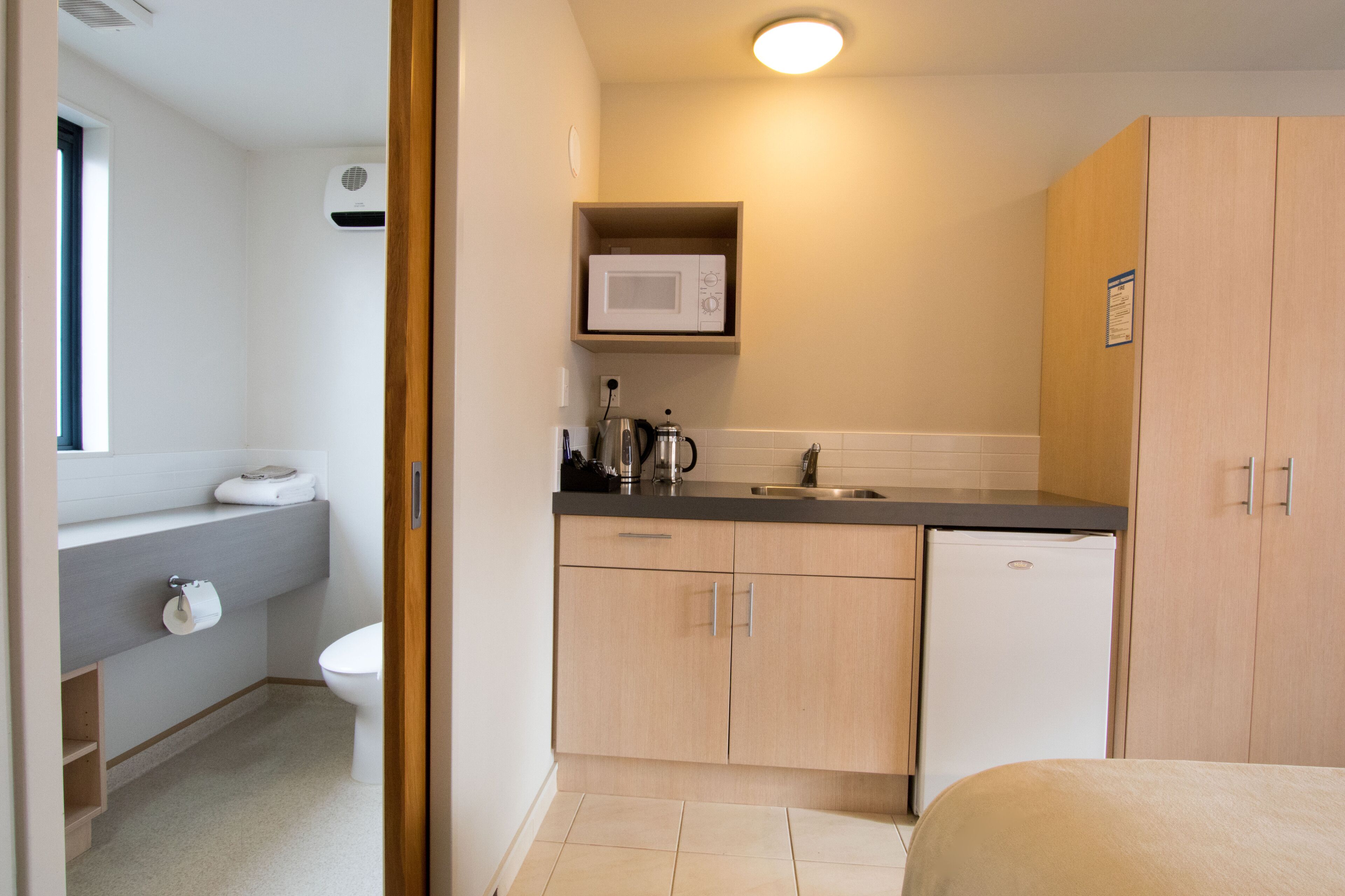 A compact kitchen with a microwave, sink, and a small refrigerator.