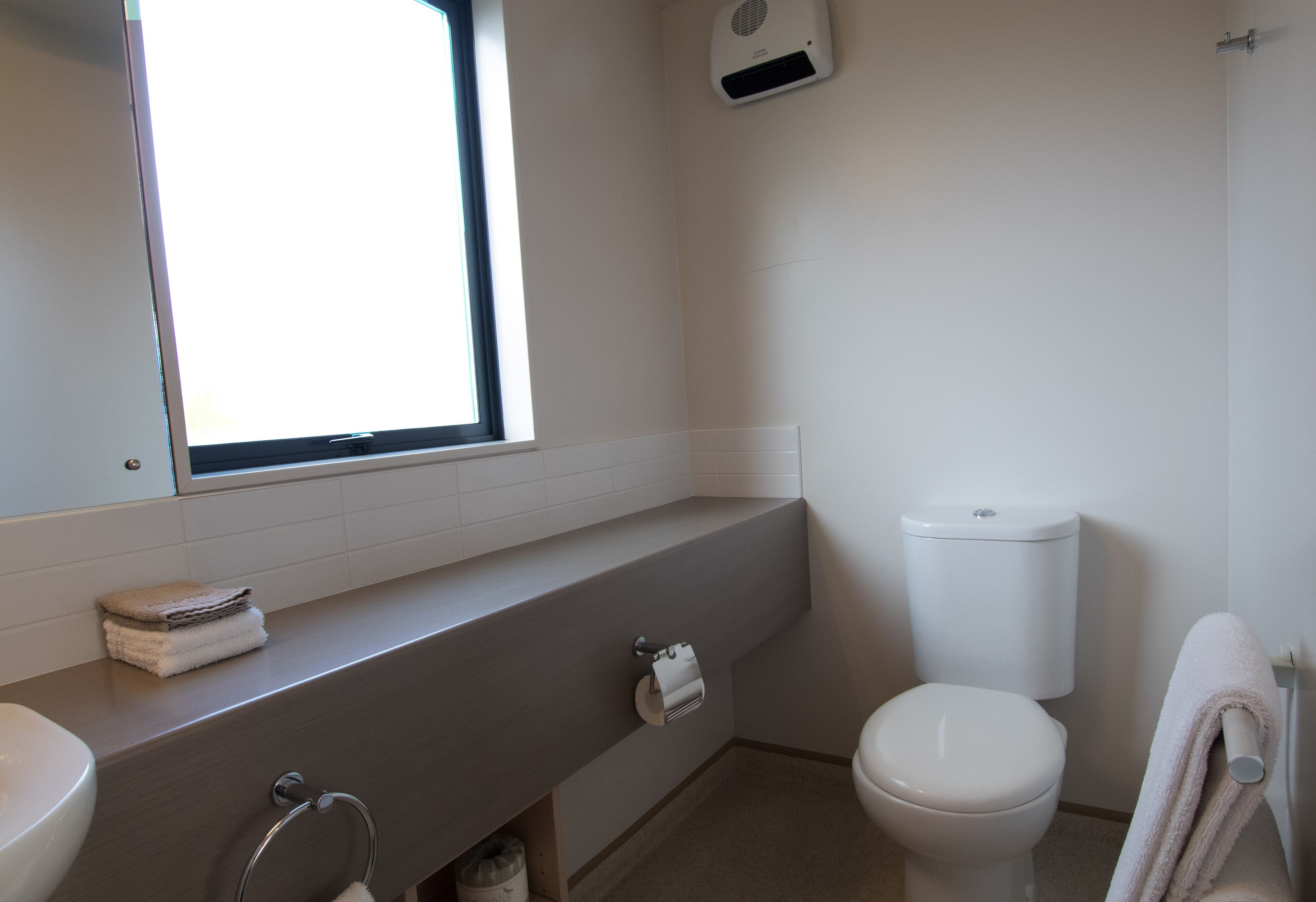 A bathroom with a toilet, sink, and towel rack.