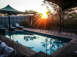 Zona de piscina con sillas de descanso y una barandilla de vidrio.