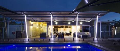 A poolside area with a covered seating area and a view into the building.