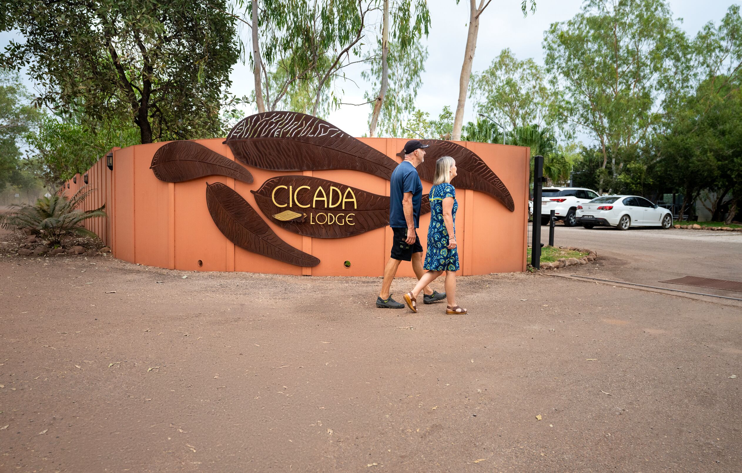 A couple walking in front of a building with a large sign reading "CICADA LODGE".