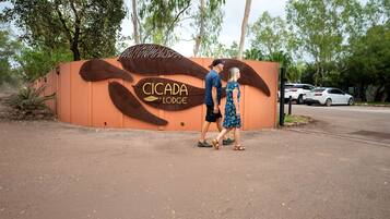 A couple walking in front of a building with a large sign reading "CICADA LODGE".