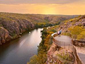 A wooden observation deck overlooking a river with rocky cliffs and autumn foliage.
