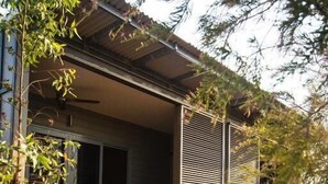 A modern house with a balcony, a small garden, and a metal fence. - Cicada Lodge (Nitmiluk)