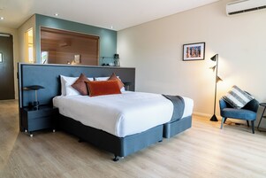 Un dormitorio moderno con una cama grande, mesitas de noche, una silla y un estante en la pared.