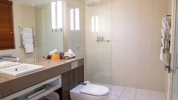 A modern bathroom with a glass shower enclosure, a white toilet, and a vanity with a mirror and sink.