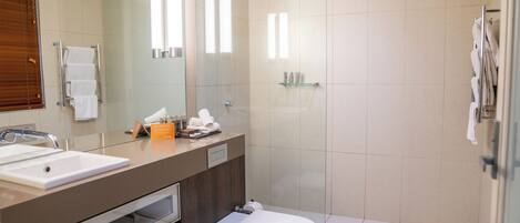 A modern bathroom with a glass shower enclosure, a white toilet, and a vanity with a mirror and sink.