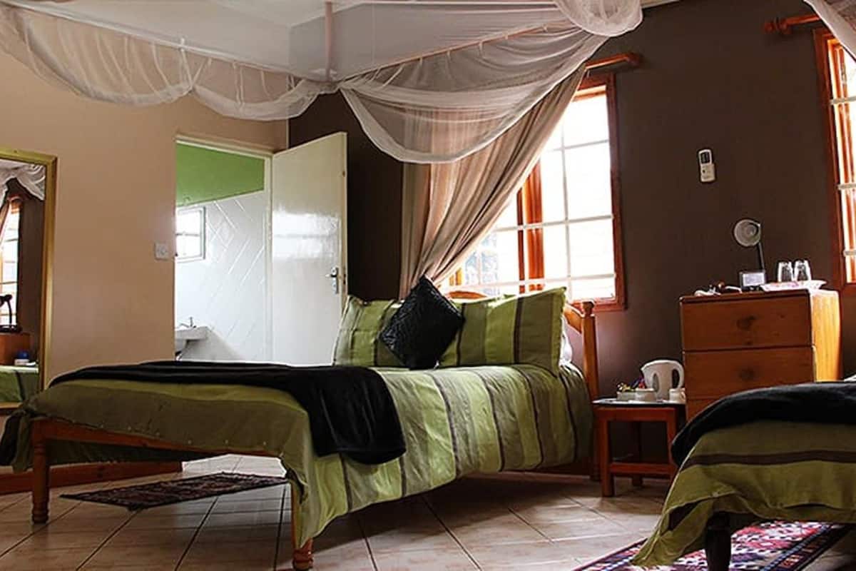 Una habitación con dos camas, un aparador, un espejo y una ventana con cortinas.