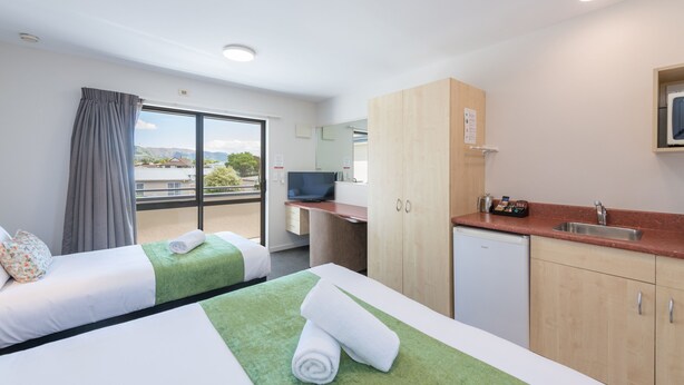 Une chambre d’hôtel avec deux lits, une petite kitchenette, une télévision et un balcon avec vue.