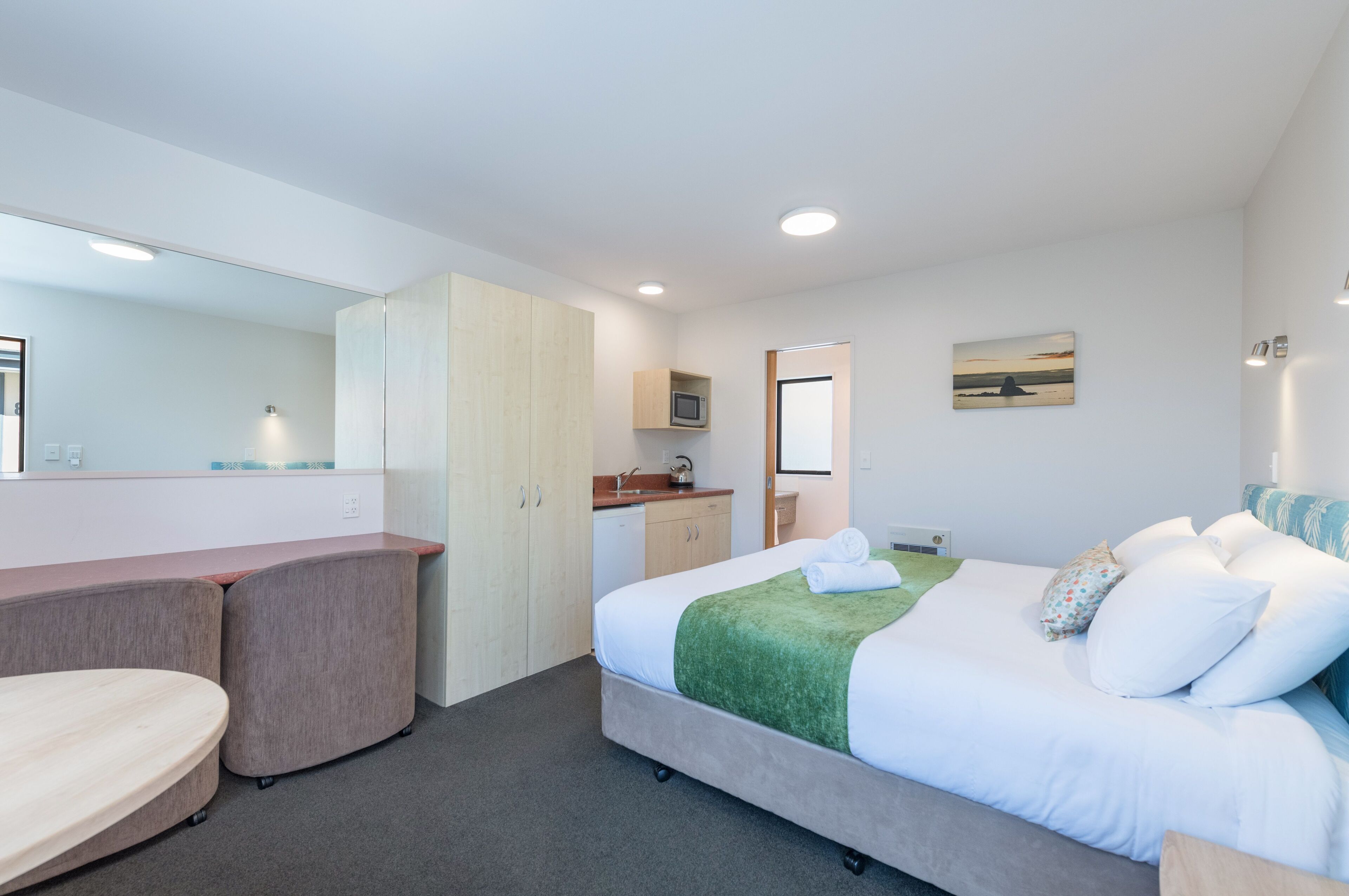 Habitación de hotel con cama, escritorio, kitchenette y baño.
