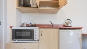 Une cuisine compacte équipée d’un four encastré, d’un four à micro-ondes et d’un lave-vaisselle.