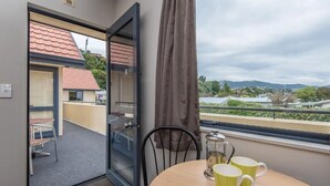 Une pièce avec vue sur un bâtiment au toit rouge, un balcon avec une chaise et une table avec deux tasses.