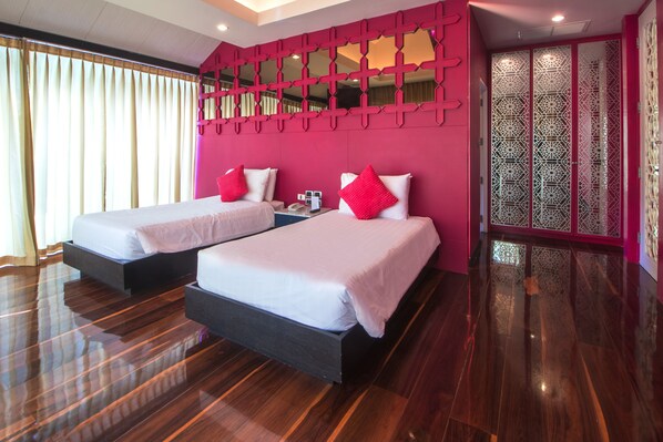 Une chambre d ’hôtel avec deux lits, un plancher en bois et un mur d’accent de couleur rose.