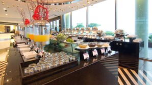 Un espace buffet comprenant différents postes de service pour les plats, des récipients en verre et un élément décoratif central.