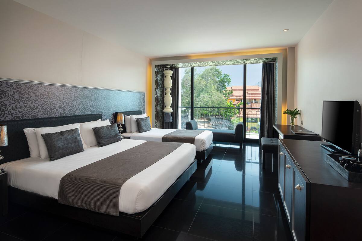 A modern hotel room with two beds, a large window with a view, a flat-screen TV, and a small balcony.