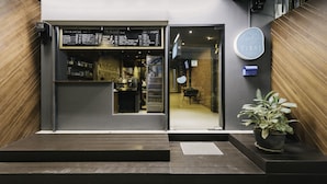 A modern coffee shop entrance with a menu board, a push button, and a potted plant. - TIRAS Patong Beach Hotel (Patong)