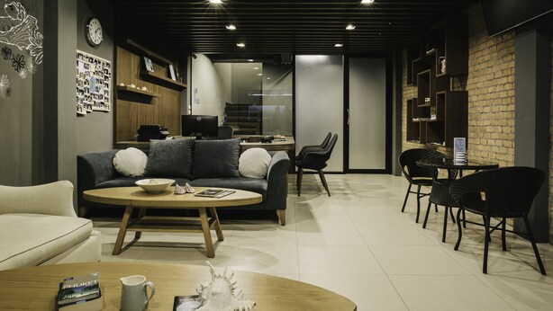 A modern living room with a sofa, coffee table, and chairs. There is a kitchen area with a refrigerator and a microwave. - TIRAS Patong Beach Hotel (Patong)