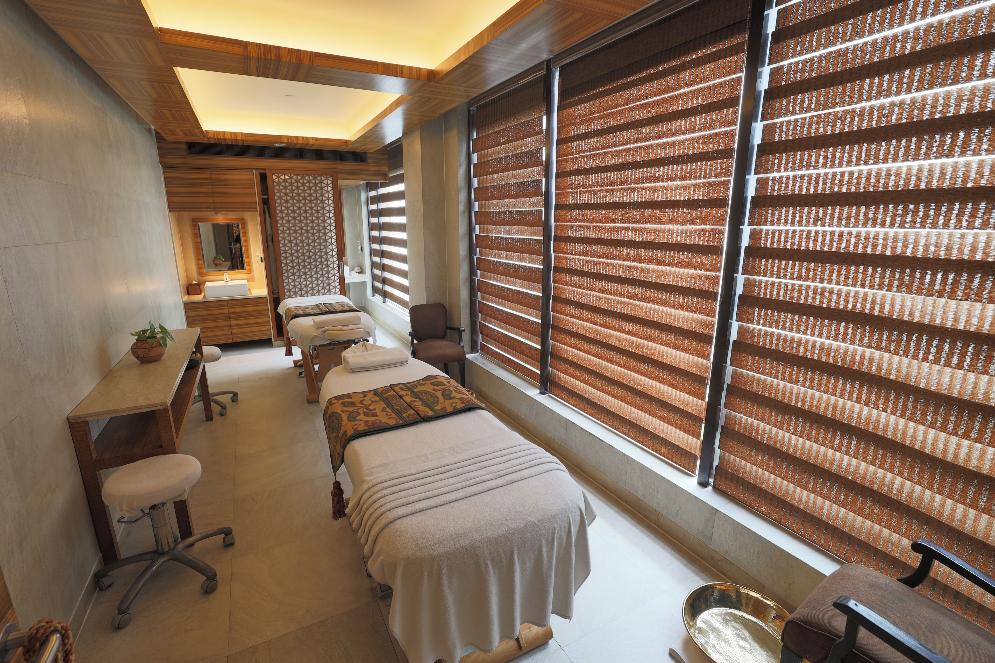 A room with a bed, a desk, a chair, and a large window with blinds.