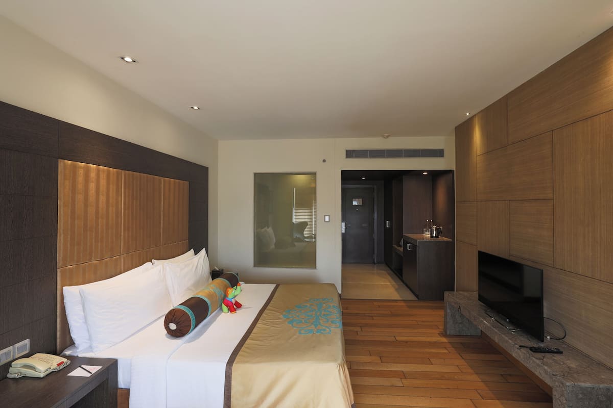 Ein modernes Hotelzimmer mit einem großen Bett, einem Fernseher und einem hölzernen Kopfteil.
