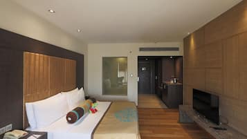 Una habitación de hotel moderna con una cama grande, televisión y cabecero de madera.