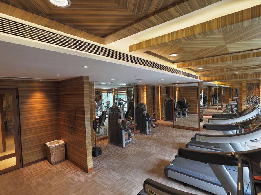 Une salle de sport équipée de tapis de course, d’appareils de musculation et de miroirs.
