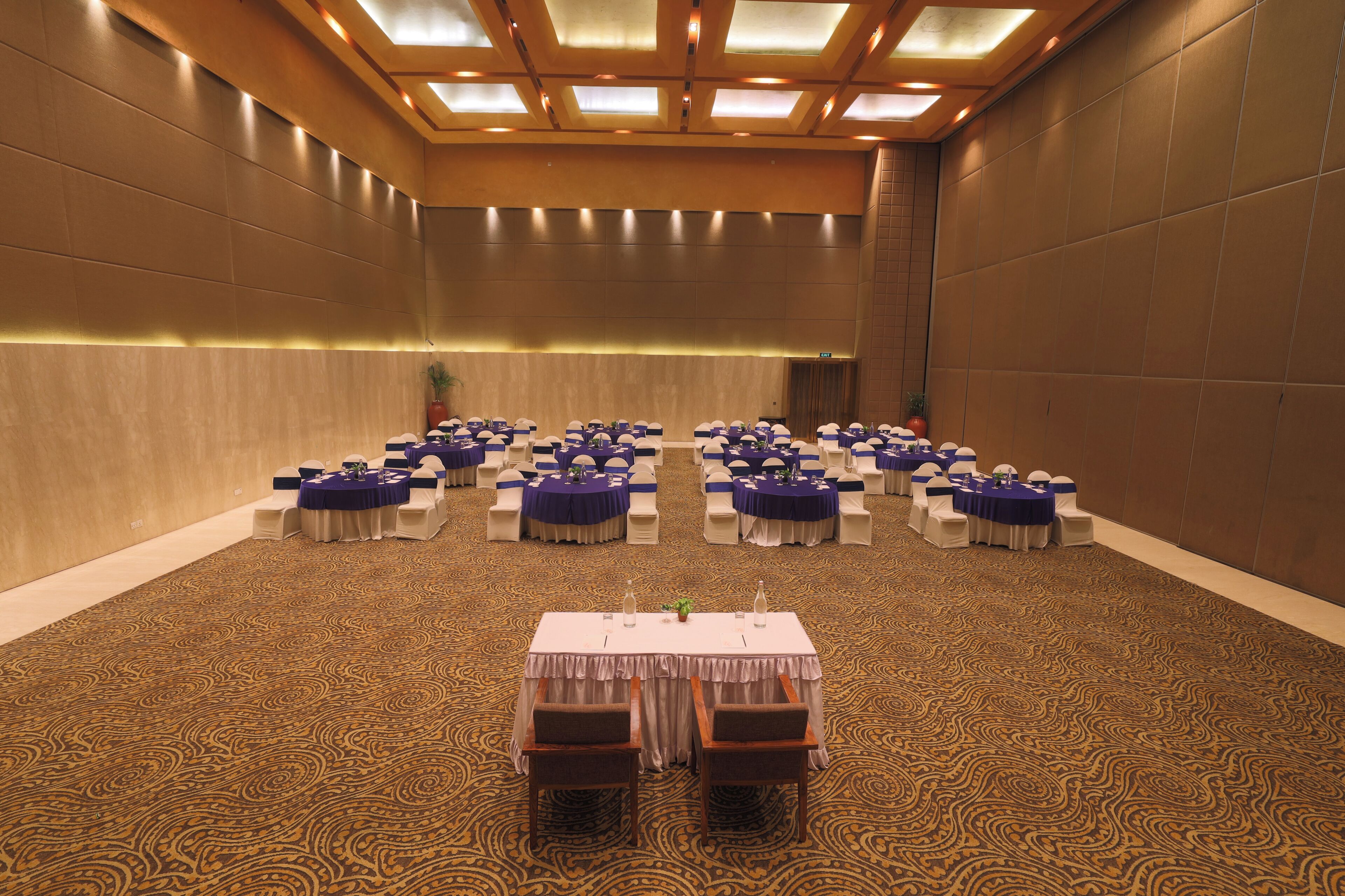 A conference room with multiple tables and chairs, arranged in rows.