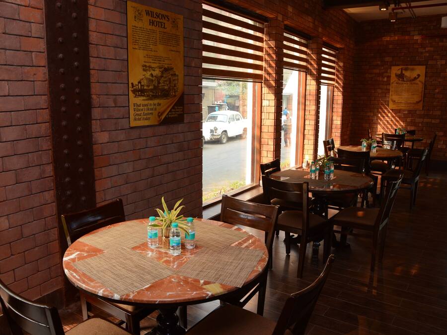 A restaurant with brick walls, wooden blinds, and tables with water bottles and plants.