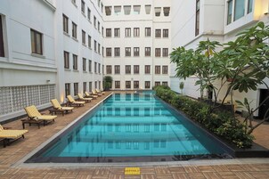 A swimming pool with lounge chairs and a building with multiple windows.