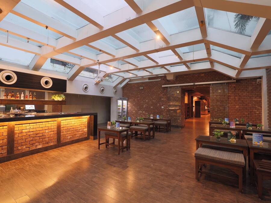 A restaurant with a brick wall, wooden tables, and a skylight.