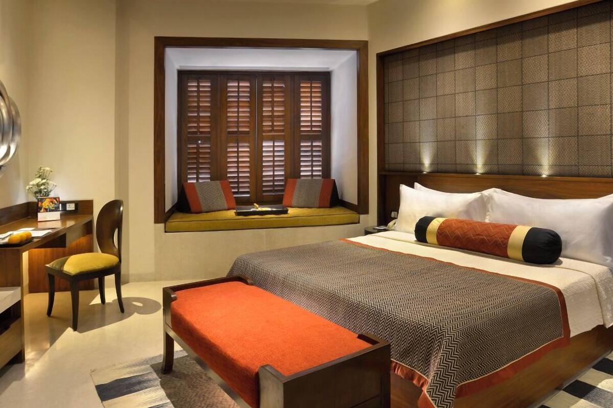 Ein Hotelzimmer mit einem großen Bett, einem Schreibtisch, einem Stuhl und einem Fenster mit Holzjalousien.