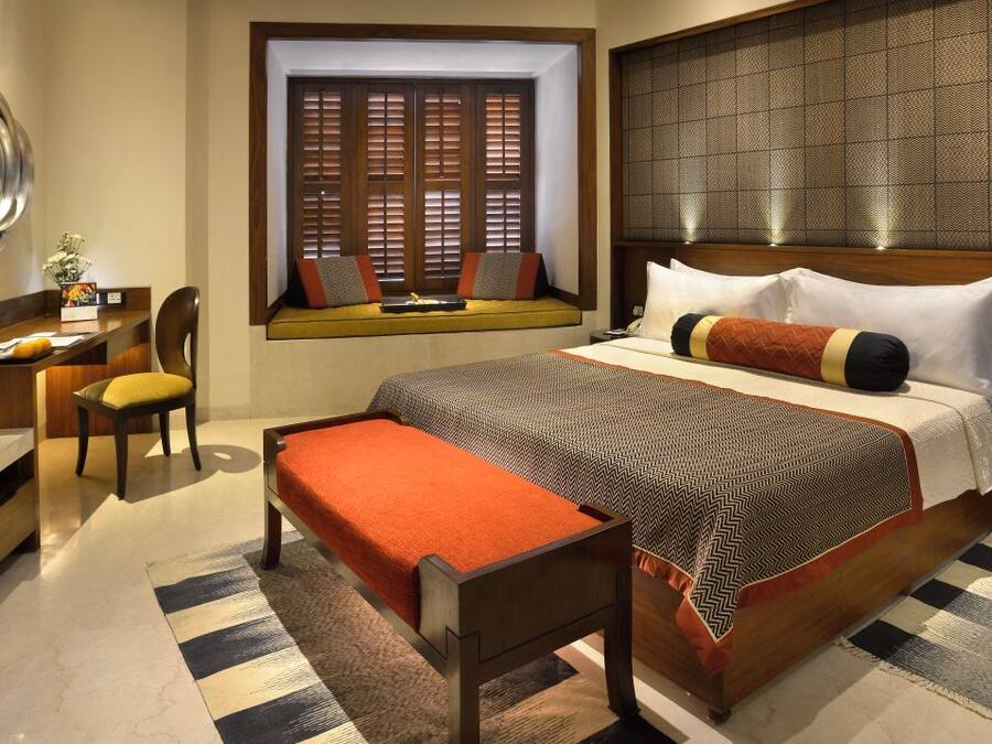 Een hotelkamer met een groot bed, een bureau, een stoel en een raam met houten luiken.
