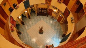 A circular atrium with a tiled floor, a central decorative area, and walls adorned with framed artwork. - Hotel Restaurant Diana (Ustica)