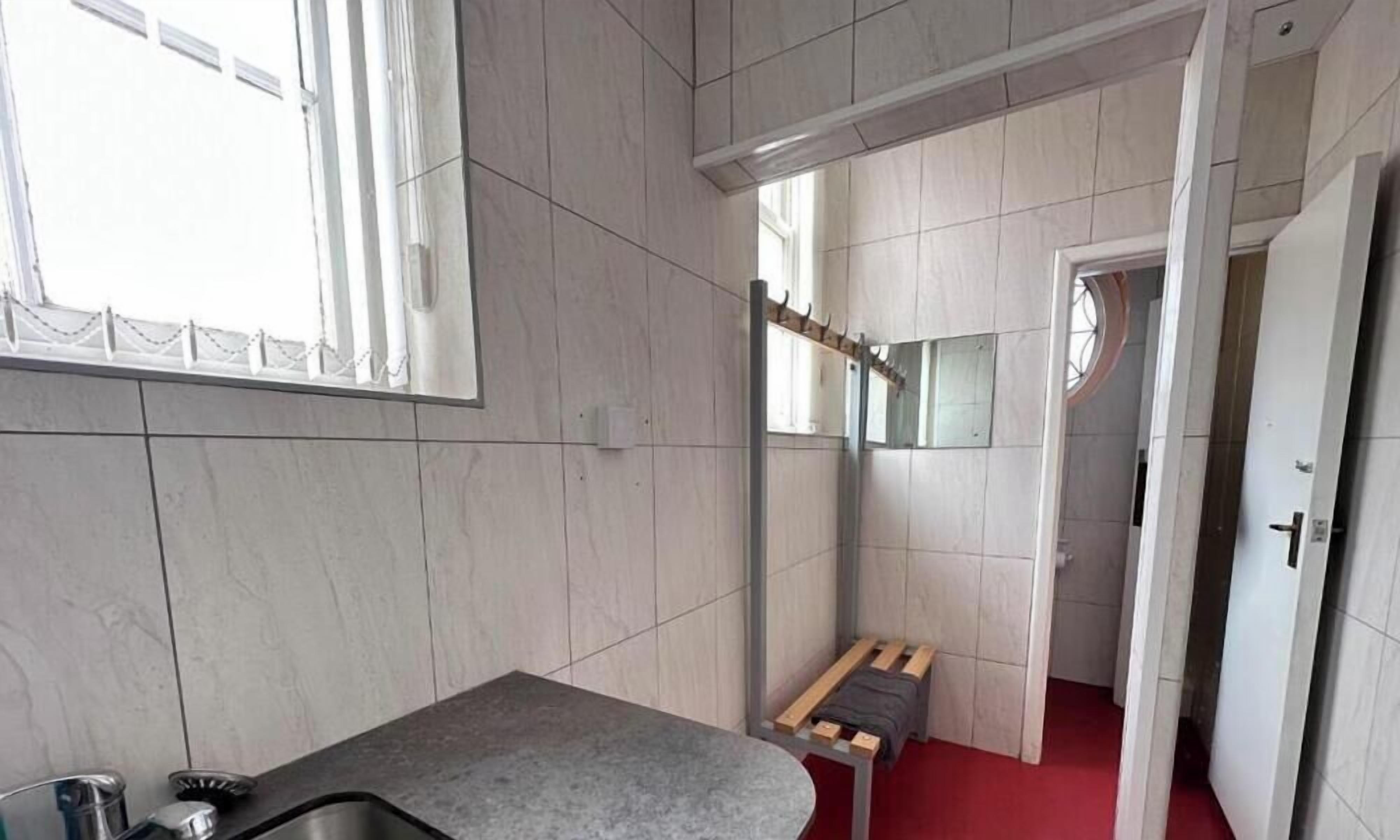 Baño con lavamanos, espejo y zona de ducha.