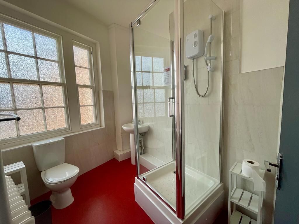 Un baño con ducha de vidrio, inodoro y lavamanos.