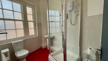 Un baño con ducha de vidrio, inodoro y lavamanos.