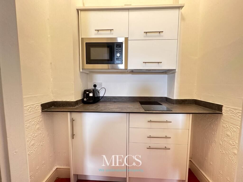A compact kitchen with a microwave, a coffee maker, and a countertop.