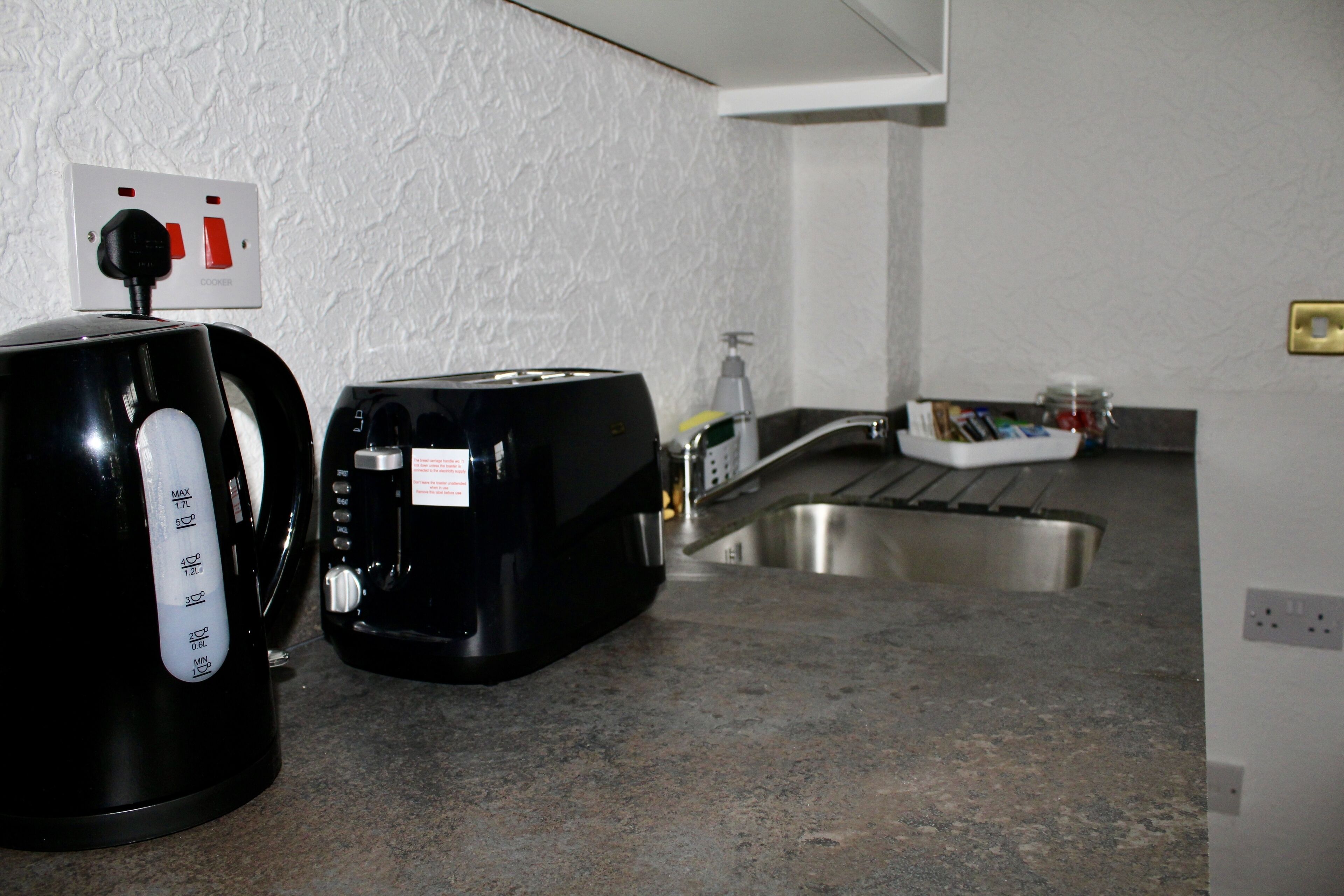 A kitchen with a coffee maker, toaster, and a sink.