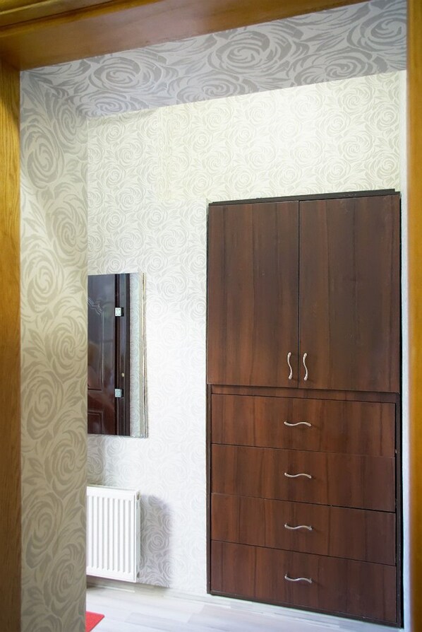 Una habitación con un armario grande de madera, un radiador y un espejo en la pared.
